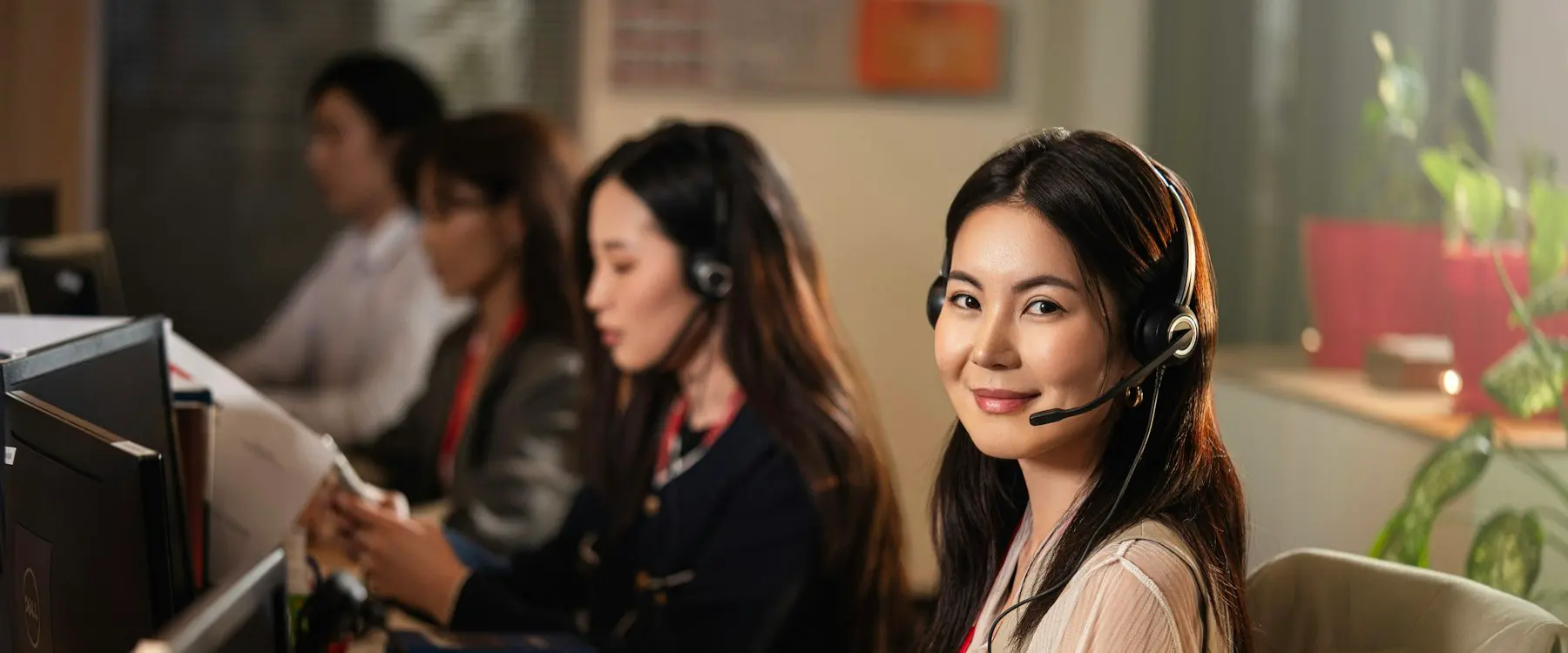 A smiling support agent wearing a headset at her computer