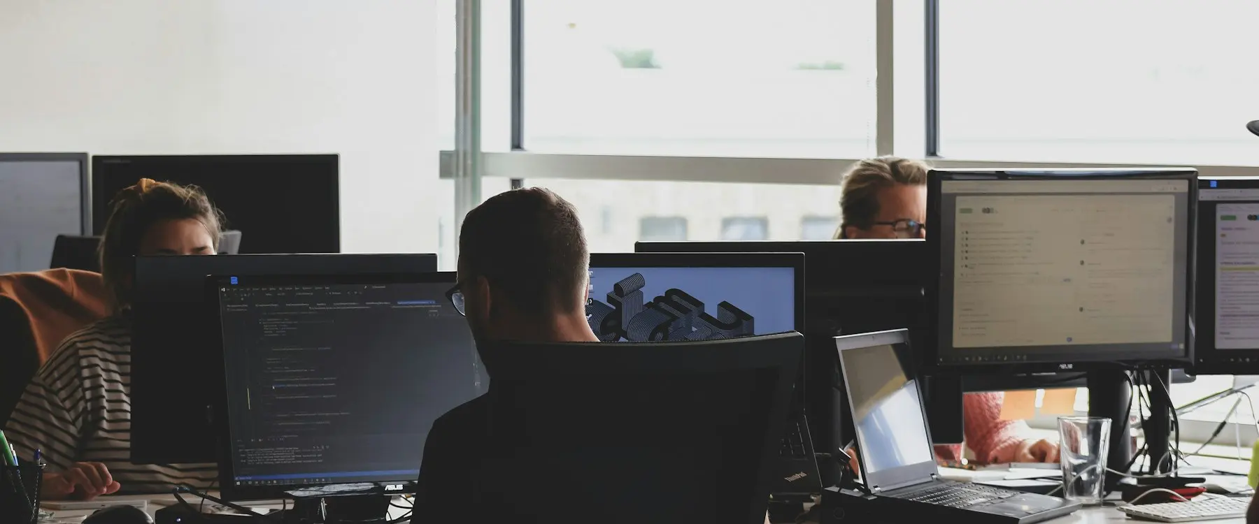 Engineers working at multiple screens in an open-plan office