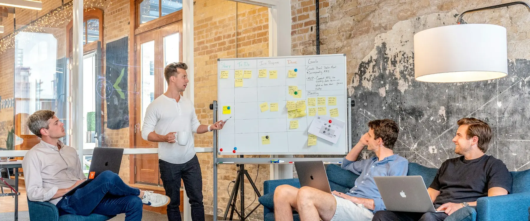 Une équipe écoute une présentation devant un tableau blanc